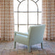 A John Robshaw Square Chair in Aleppo Sage Performance Fabric is upholstered in a light blue tone and positioned on a tiled floor, facing a large arched window with patterned beige curtains.