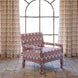 A Square Chair in Lanka Berry and Aleppo Berry by John Robshaw, featuring a red and cream pattern, sits on a tiled floor in front of matching curtains and a large arched window.