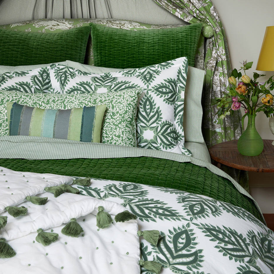 A hand-quilted Velvet Moss Quilt bed with green and white velvet bedding and pillows, created by Indian artisans, by John Robshaw.
