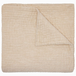 The Vivada Sand Woven Quilt by John Robshaw is shown here neatly folded with one corner turned over, highlighting the luxurious texture and substantial thickness of its cotton fabric—a refined addition to our reversible quilt collection, thoughtfully designed for comfort and style.