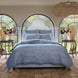 A bed with a simple Nandi Indigo Quilt by John Robshaw and arched windows.