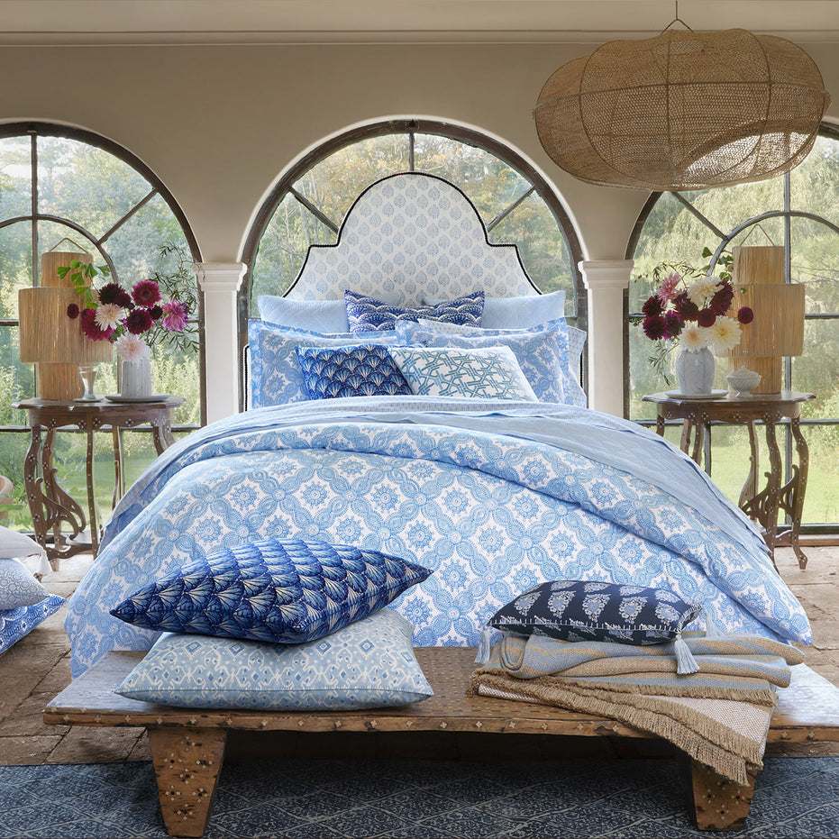 A bedroom with the John Robshaw Nandi Light Indigo Quilt, blue and white bedding, and pillows.