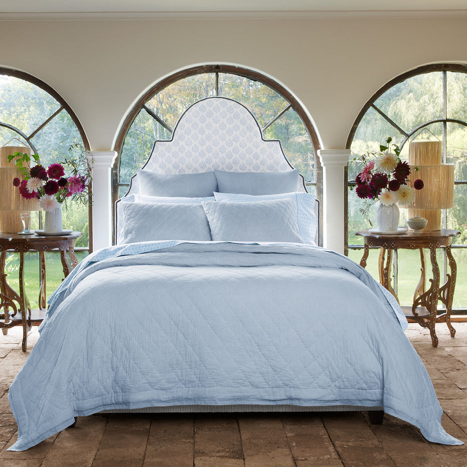 A cotton voile bed with a Nandi Light Indigo Quilt by John Robshaw and arched windows.