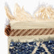Corner of a Blue Village Wool Rug featuring a blue and cream patterned pile, a brown and cream geometric border, and long fringe at the top edge.