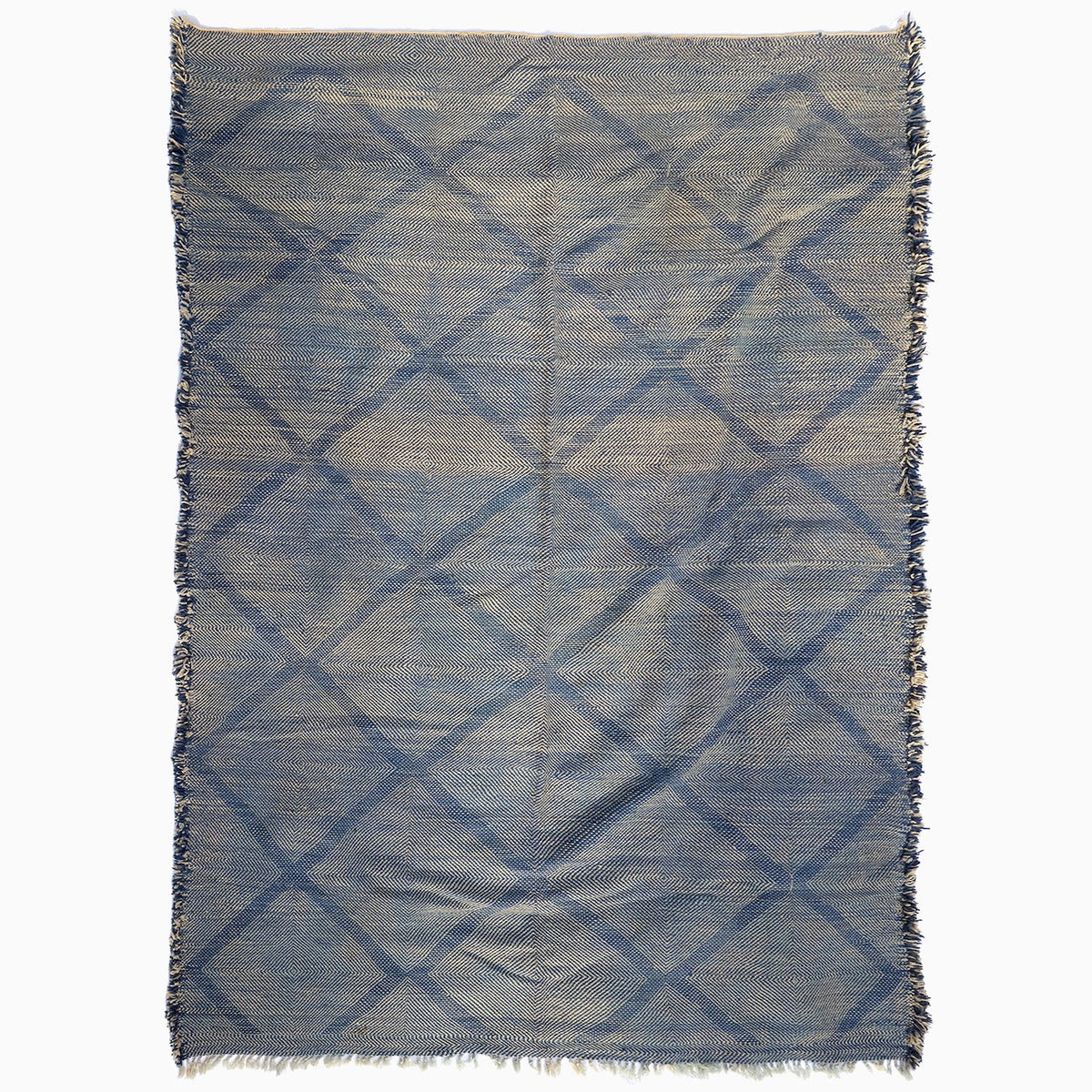 John Robshaw Big Zanafi Wool Rug, a handwoven rectangular rug featuring a blue and white diamond pattern and fringed edges, inspired by traditional Berber designs.