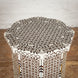The Karigar Table by John Robshaw is an octagonal wooden table featuring an intricate geometric inlay design in white and brown, handcrafted from premium Indian hardwood and inspired by traditional bone inlay furniture, displayed against a white brick wall and wooden floor.