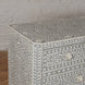 A close-up of the Vajra Bone Inlay Sideboard by John Robshaw showcases its intricate white and gray floral patterns, set against a white brick wall and wooden floor, making it a stunning statement piece for any room.
