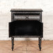 The John Robshaw Ahan Bone Inlay Cabinet showcases intricate black and white geometric patterns, featuring one drawer and an open cabinet door, all standing on four tapered legs against a white brick wall.