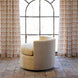 A John Robshaw Round Swivel Chair in Farzu Marigold and Bijal Sand sits on a tile floor in front of a large arched window framed by patterned curtains.