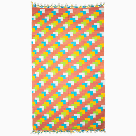 A vibrant beach towel featuring a stylish pattern of triangles, reminiscent of vintage rugs from Punjab's weaving centers, the Left to Right Then Back Again Rug by John Robshaw.