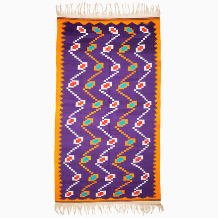 A vintage purple and orange John Robshaw Music Rug with fringes, handmade at a weaving center in Punjab.