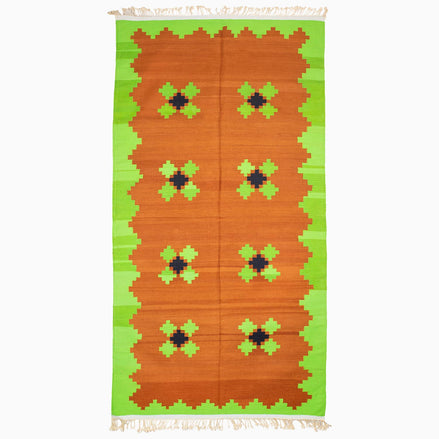 A Lime and Tea Rug in orange and green with a geometric pattern, handcrafted by the John Robshaw weaving center.