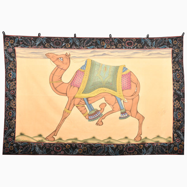 John Robshaw Trotting Camel Tapestry featuring a hand-painted camel in a saddle and beaded anklets, framed by a dark floral border.