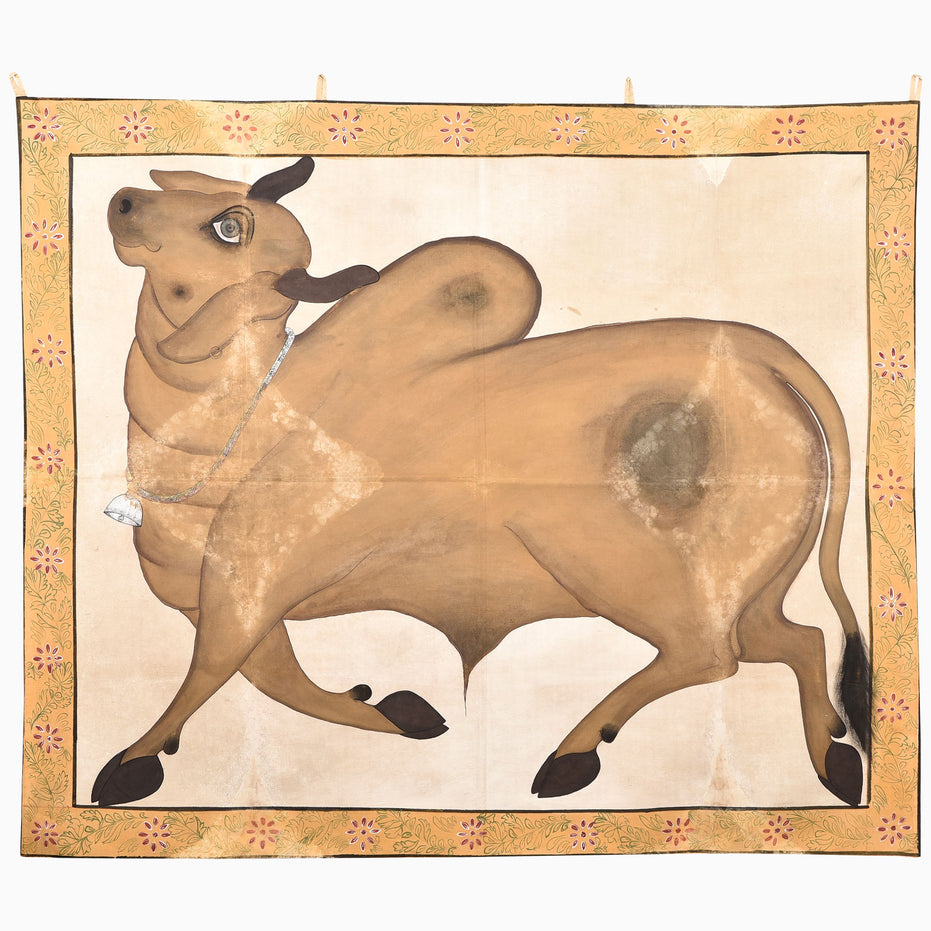 We Gallop Tapestry featuring a hand-painted tan zebu wearing a bell on a chain, framed by a floral border.