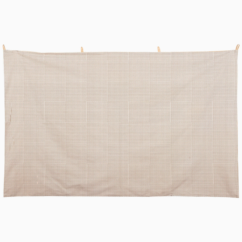 A Watchful Stance Tapestry is a rectangular fabric wall hanging featuring a dense, repeating brown and cream geometric pattern inspired by Indian folk art.