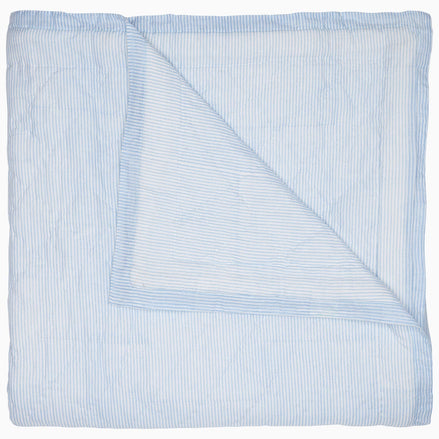 A Nandi Light Indigo quilt by John Robshaw with blue and white striped block printing.
