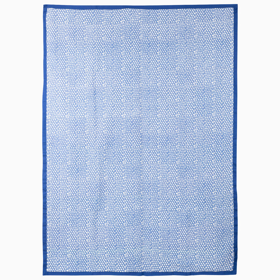 Rectangular vintage Azure Bloom Suzani blanket by John Robshaw with a blue and white geometric grid pattern and a solid blue border.