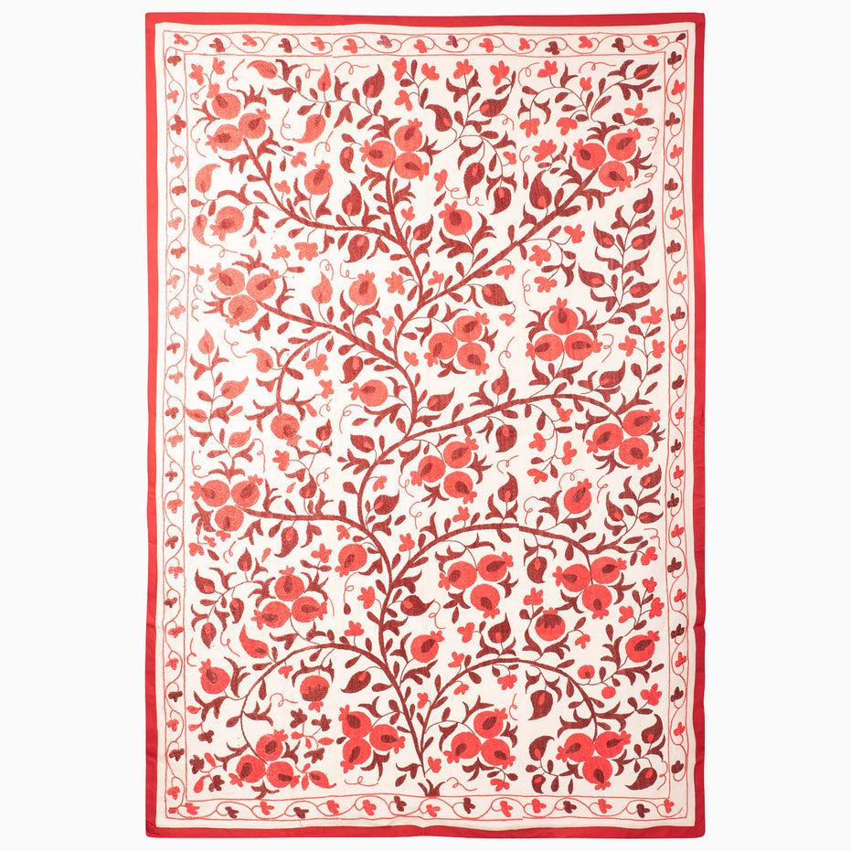 John Robshaw Harvest Poppy Suzani blanket in a rectangular, vintage style with a red-and-white botanical pattern of scrolling pomegranate vines and flowers enclosed by a solid red border.