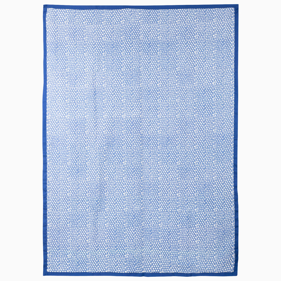 Jaipur Twilight Suzani Blanket featuring a blue and white geometric grid pattern with embroidered botanical motifs and a solid blue border.