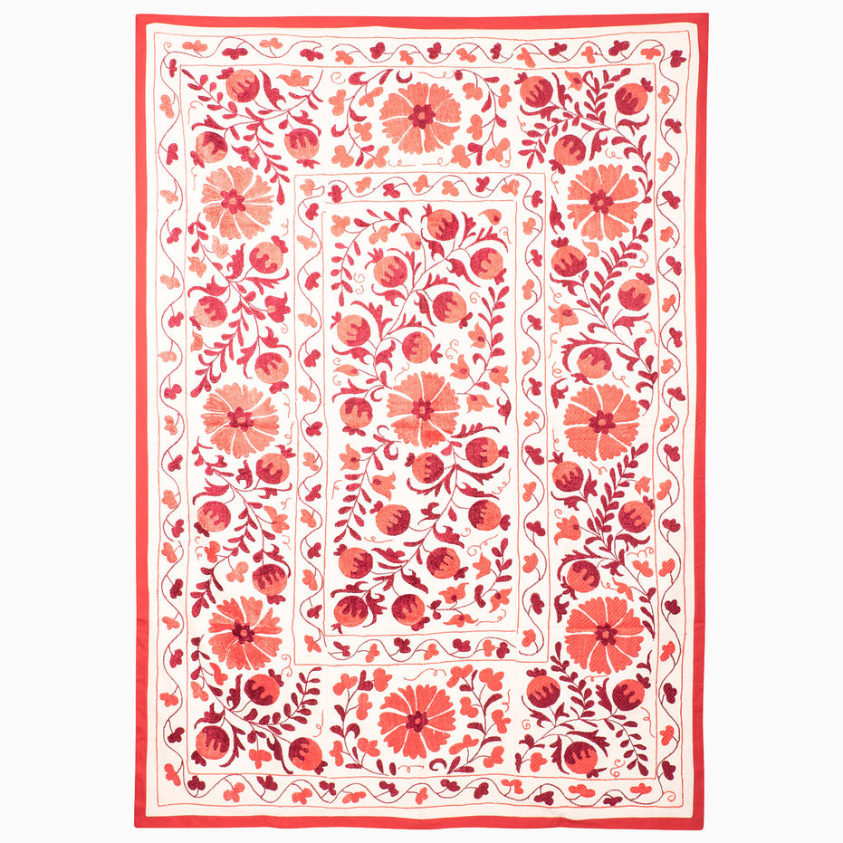 A rectangular John Robshaw Red Clay Suzani blanket made of white textile featuring red floral and pomegranate embroidery in a vintage pattern.