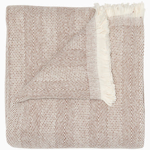 The Lavanya Coffee Throw by John Robshaw features a folded beige and brown herringbone weave with fringed edges, showing both front and back sides.