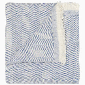 Lavanya Indigo Throw by John Robshaw features a folded herringbone weave, indigo cotton with fringe on one edge, and a flipped corner to highlight its texture.