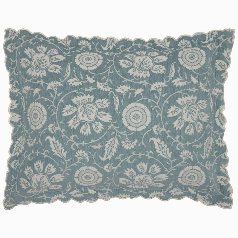 The John Robshaw Kimari Mist Coverlet showcases a blue background adorned with delicate woven florals, crafted from soft jacquard cotton chenille and finished with scalloped edges.