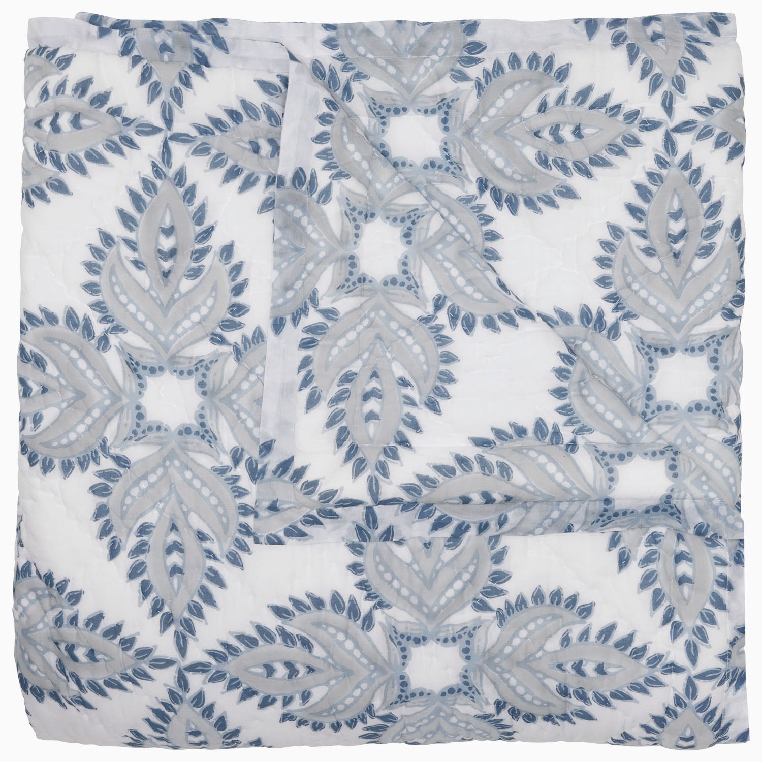 Folded John Robshaw's Dasati Lapis Quilt, featuring a blue and gray geometric leaf pattern on a white background, crafted from cotton voile.
