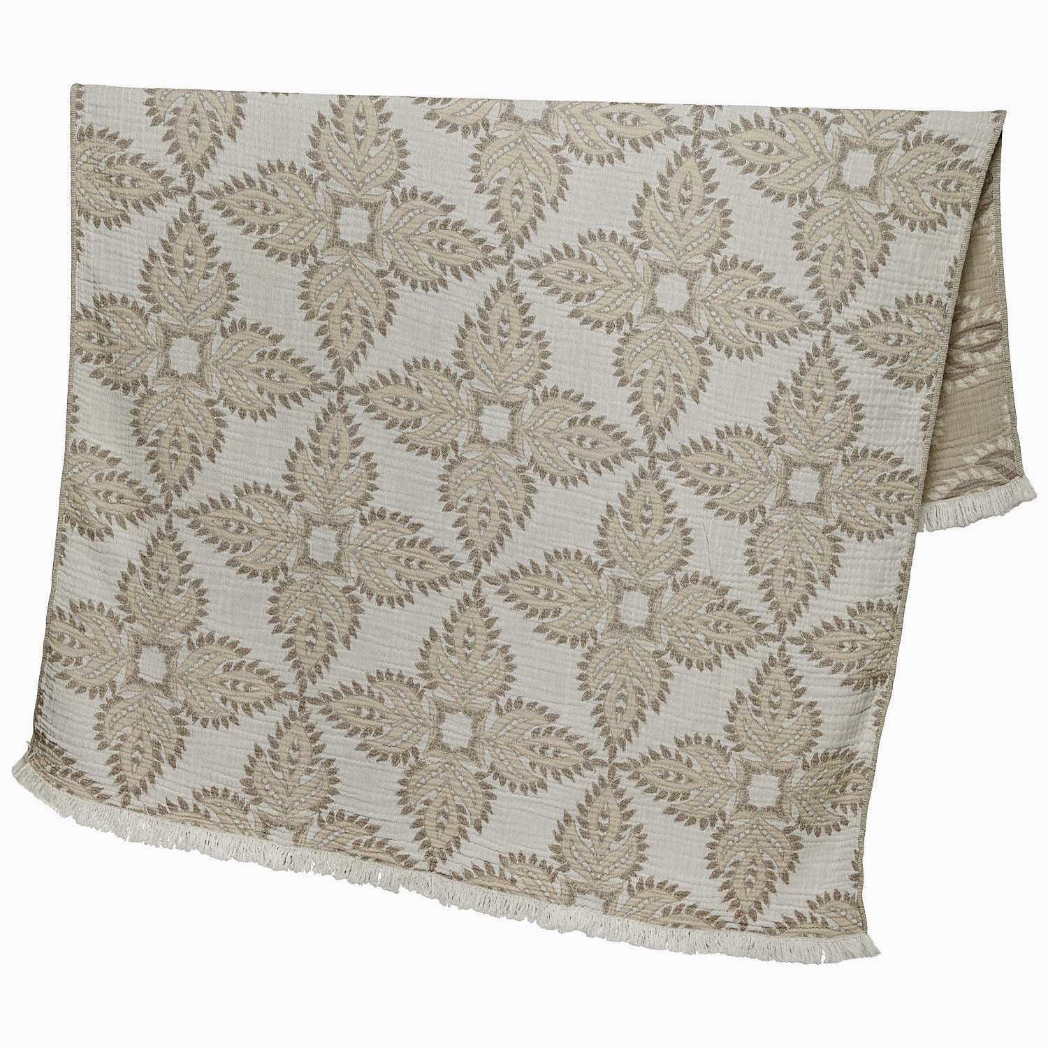 A John Robshaw Dasati Sand Throw, featuring a beige fabric with an intricate leaf-like woven design and fringed edging, draped open against a plain background.