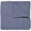 A Vivada Indigo Woven Quilt by John Robshaw folded on top of itself.