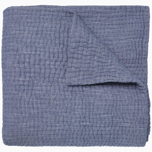 A Vivada Indigo Woven Quilt by John Robshaw folded on top of itself.