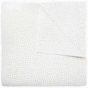 A white cotton voile coverlet featuring John Robshaw's Organic Hand Stitched Sand Quilt with subtle white dot patterns.
