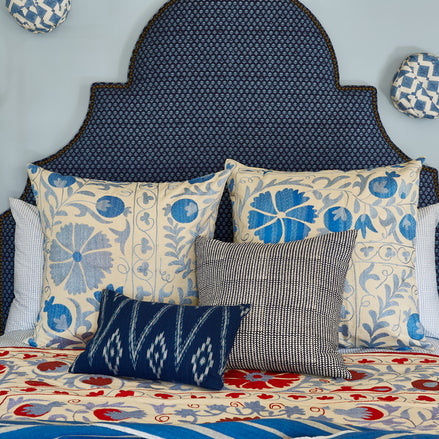 A Custom Dara Headboard by John Robshaw with blue, red and white pillows available for white glove delivery.