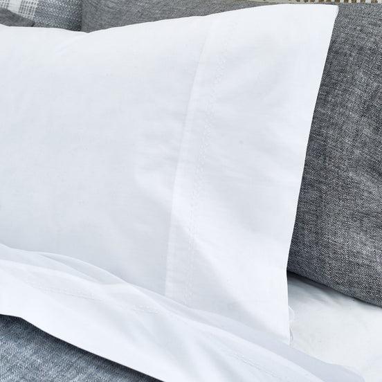 An image of a bed with John Robshaw's Anketi White Organic Sheet Set and pillows.