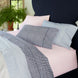 A 100% cotton percale bed with blue, pink, and white bedding, including a John Robshaw Cinde Light Indigo Organic Sheet Set.