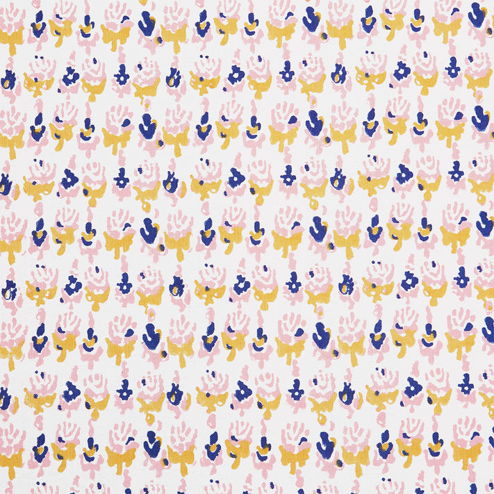 A close up of a Kiki Oyster Fabric hand block printed pink, blue and yellow flower batik by John Robshaw.