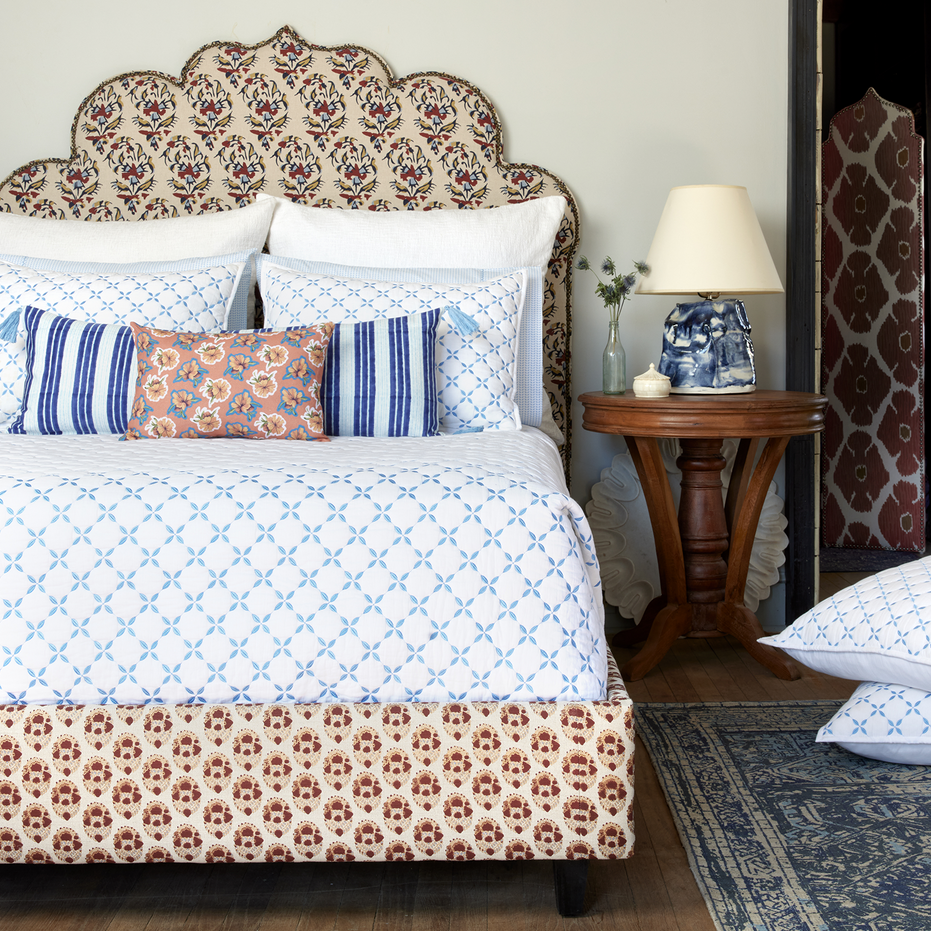 A blue and white bedroom with a bed, pillows, and John Robshaw Layla Azure Quilts.