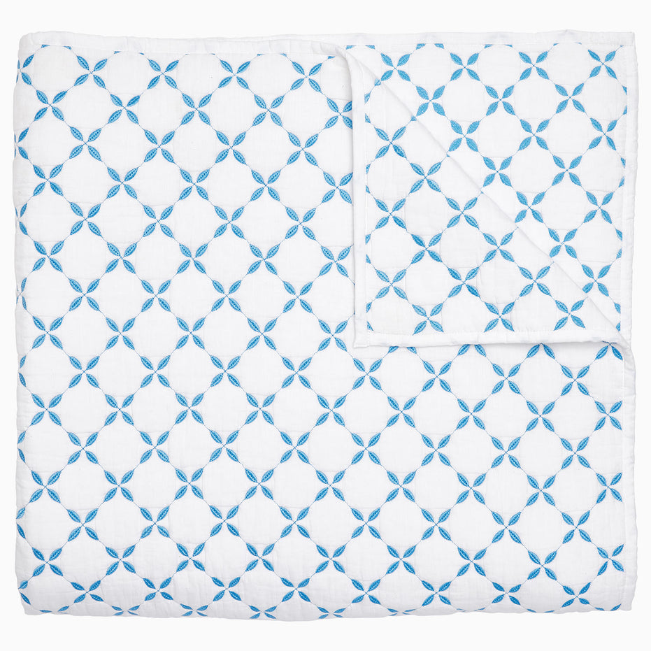 A Layla Azure Quilt by John Robshaw, a cotton voile blue and white blanket with a geometric pattern inspired by Mughal gardens.