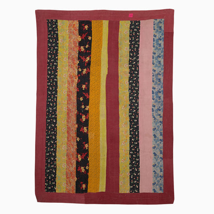 A John Robshaw Sit Up Please quilt hanging on a wall in India.
