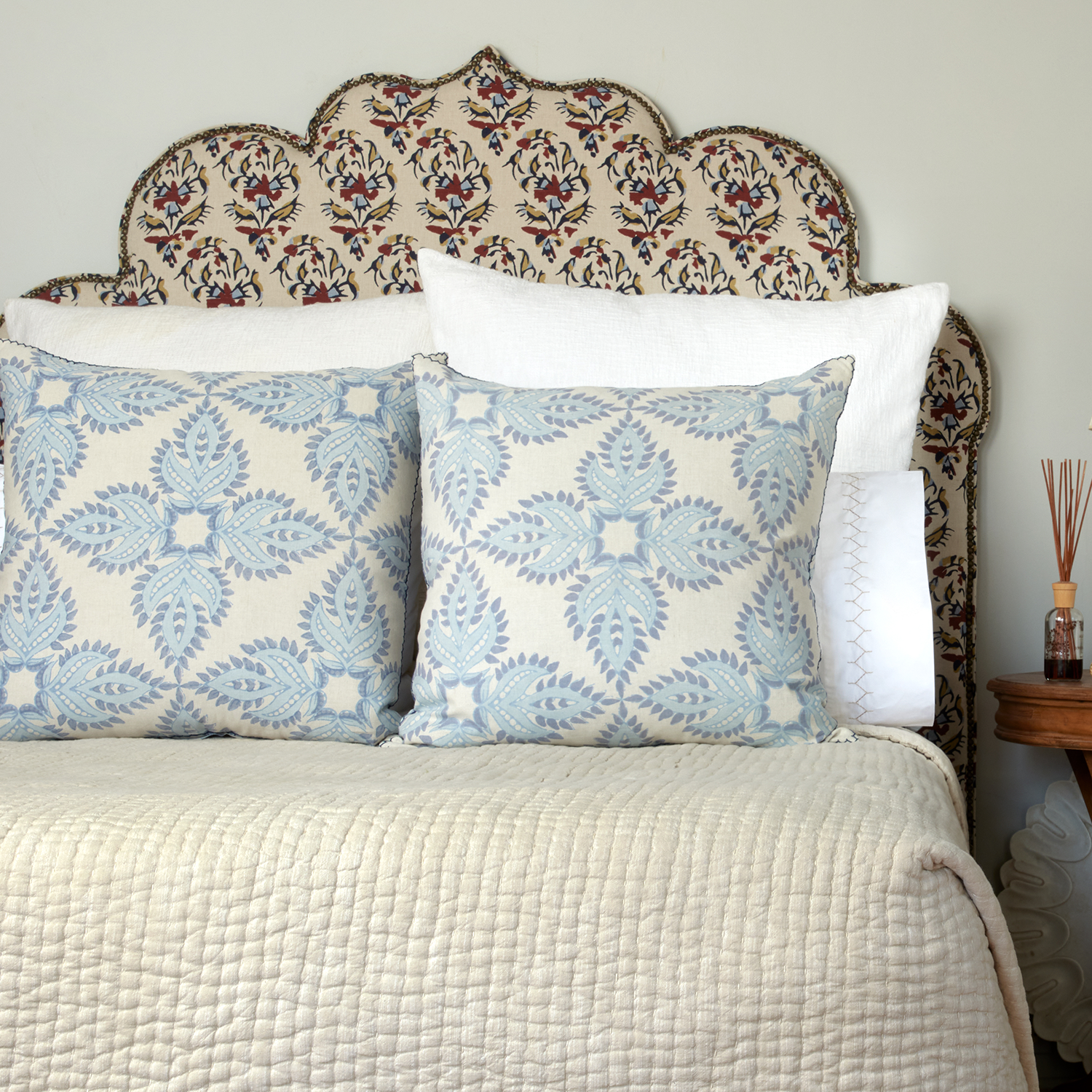 A John Robshaw Verdin Lapis Euro bed with pillows and a headboard.