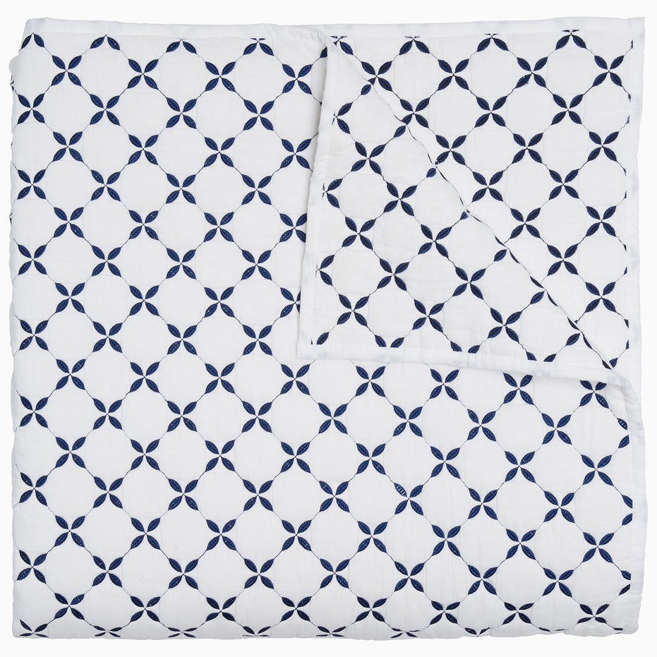 A blue and white Layla Indigo Quilt blanket with a cross design by John Robshaw.