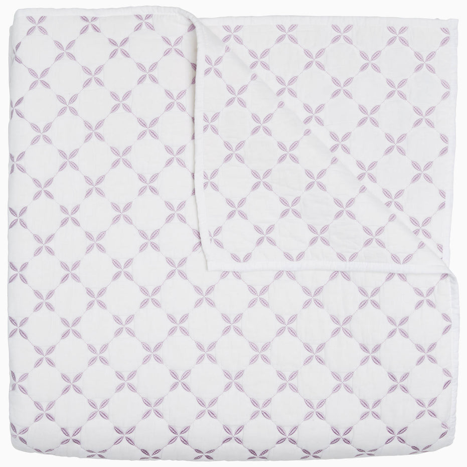 A Layla Lavender quilt by John Robshaw, made from cotton voile, with a cross pattern in white and purple, inspired by Mughal gardens.