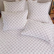 A bed featuring a Layla Lavender Quilt by John Robshaw, adorned with matching pillows.