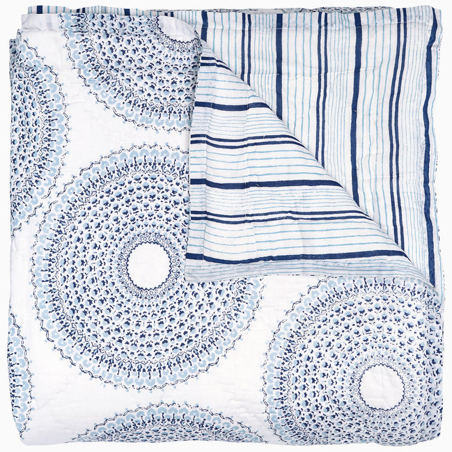 A handcrafted Lapis Quilt with a circular pattern, featuring a vintage woodblock design by John Robshaw.