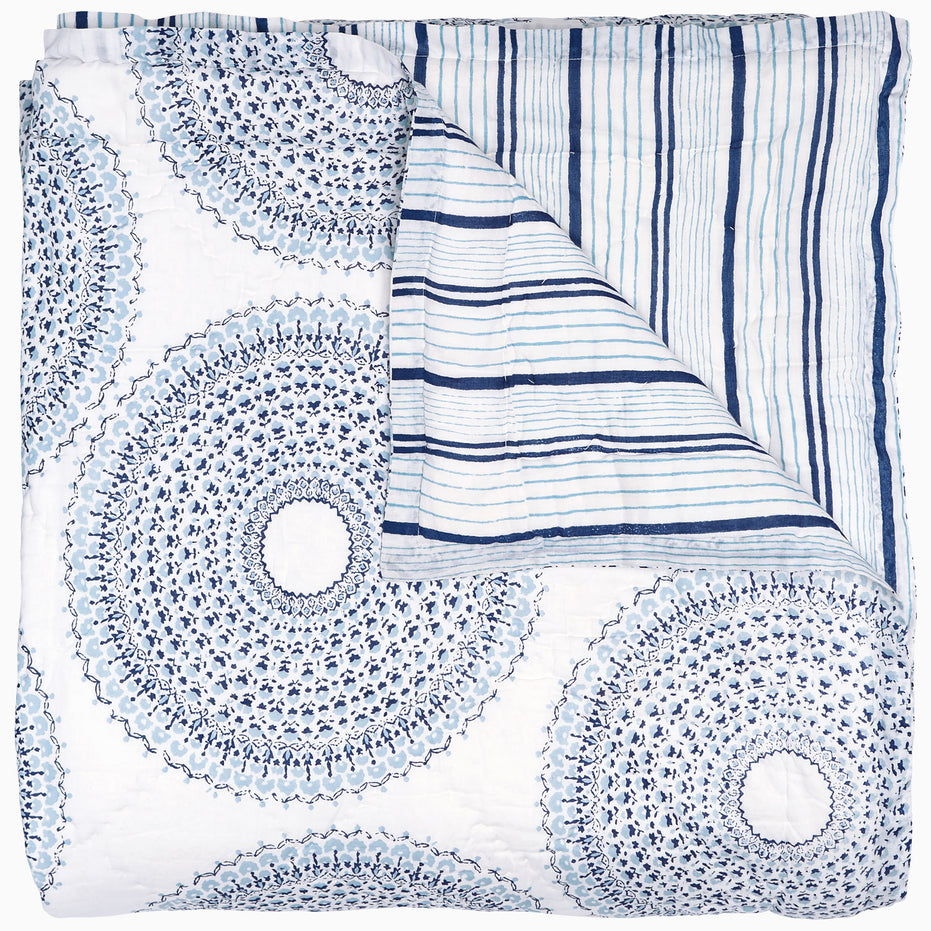 A handcrafted Lapis Quilt with a circular pattern, featuring a vintage woodblock design by John Robshaw.