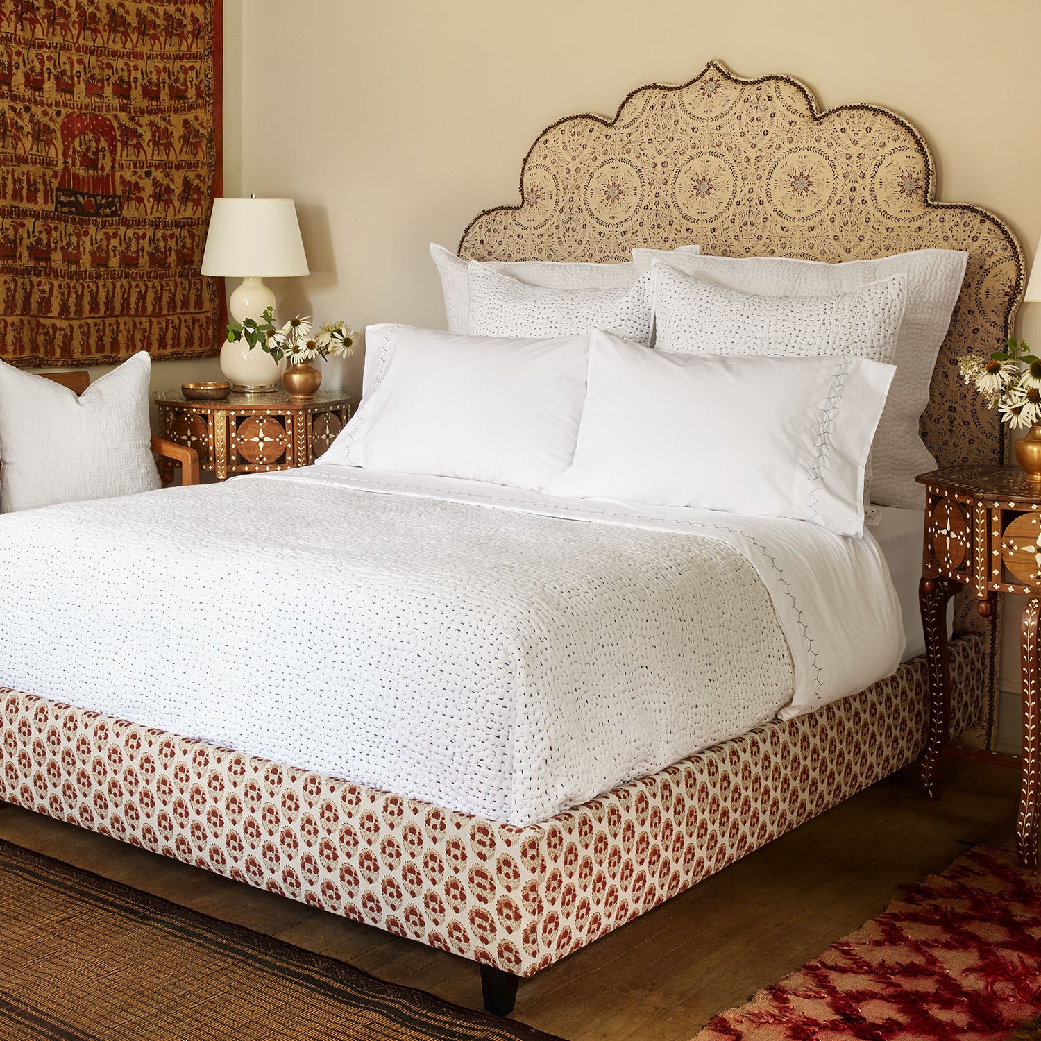 A John Robshaw Custom Bihar Bed with an ornate headboard, covered in fabric, in a bedroom.