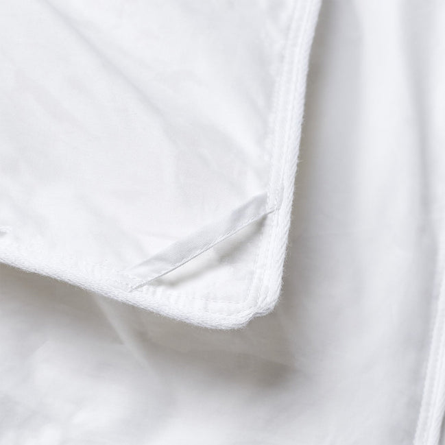 A close up of a white John Robshaw Down Alternative Comforter with a zipper.
