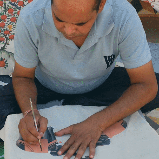 A man is hand painting an elephant on a piece of paper, inspired by the Two Elephants Decorative Pillow design by John Robshaw.