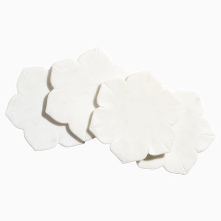 Four John Robshaw hand-carved marble coasters on a white surface.